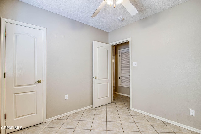 unfurnished bedroom with a textured ceiling, light tile flooring, and ceiling fan