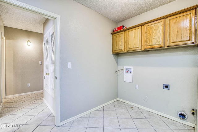 washroom featuring hookup for a washing machine, a textured ceiling, light tile flooring, and hookup for a gas dryer