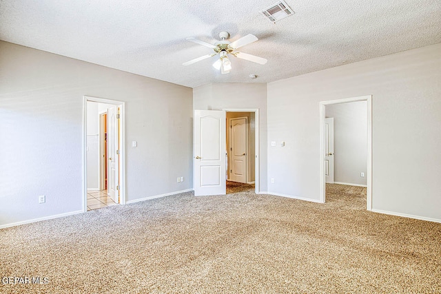 unfurnished bedroom featuring light carpet, connected bathroom, ceiling fan, and a textured ceiling