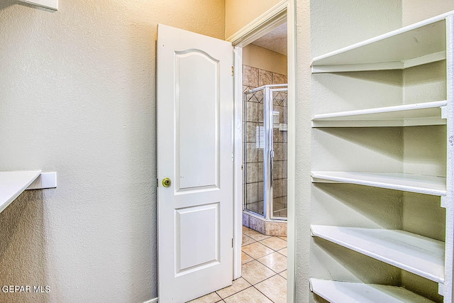 interior space with a shower with shower door and tile flooring