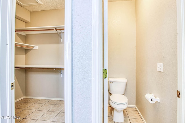 bathroom featuring a textured ceiling, toilet, and tile floors