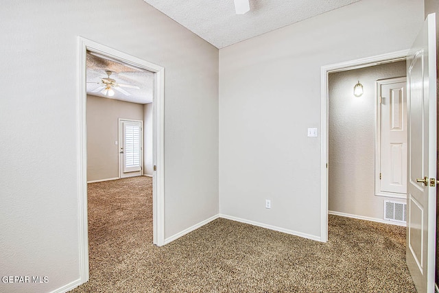 spare room featuring a textured ceiling, dark colored carpet, and ceiling fan