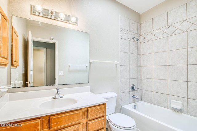 full bathroom with tiled shower / bath, toilet, and large vanity