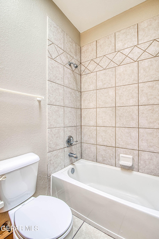 bathroom with tile flooring, toilet, and tiled shower / bath combo