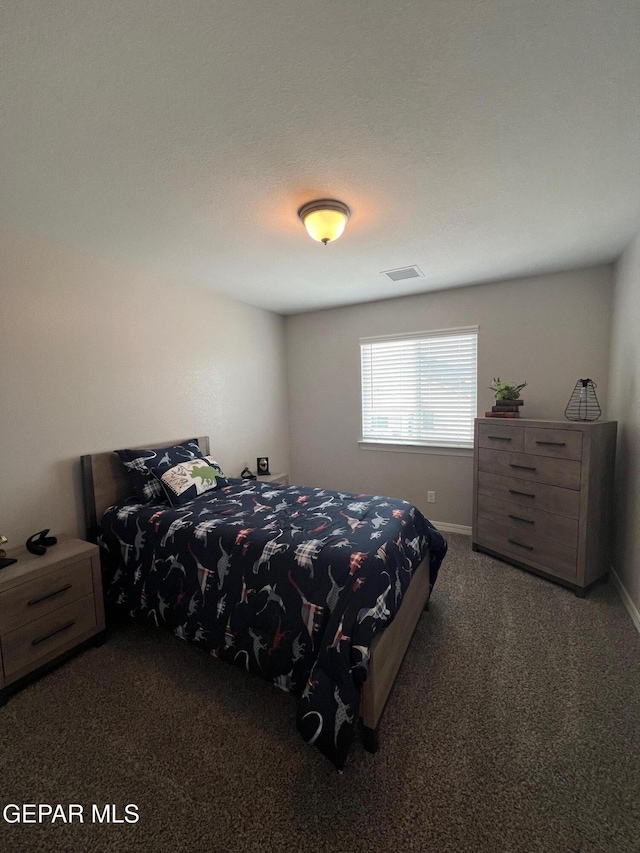 bedroom featuring dark colored carpet, visible vents, and baseboards