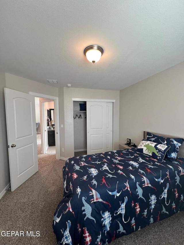 bedroom featuring baseboards, visible vents, a textured ceiling, carpet floors, and a closet