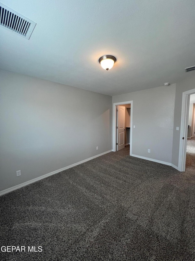 unfurnished bedroom featuring dark colored carpet, visible vents, and baseboards