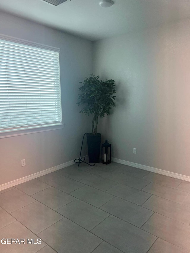 spare room featuring light tile patterned floors and baseboards