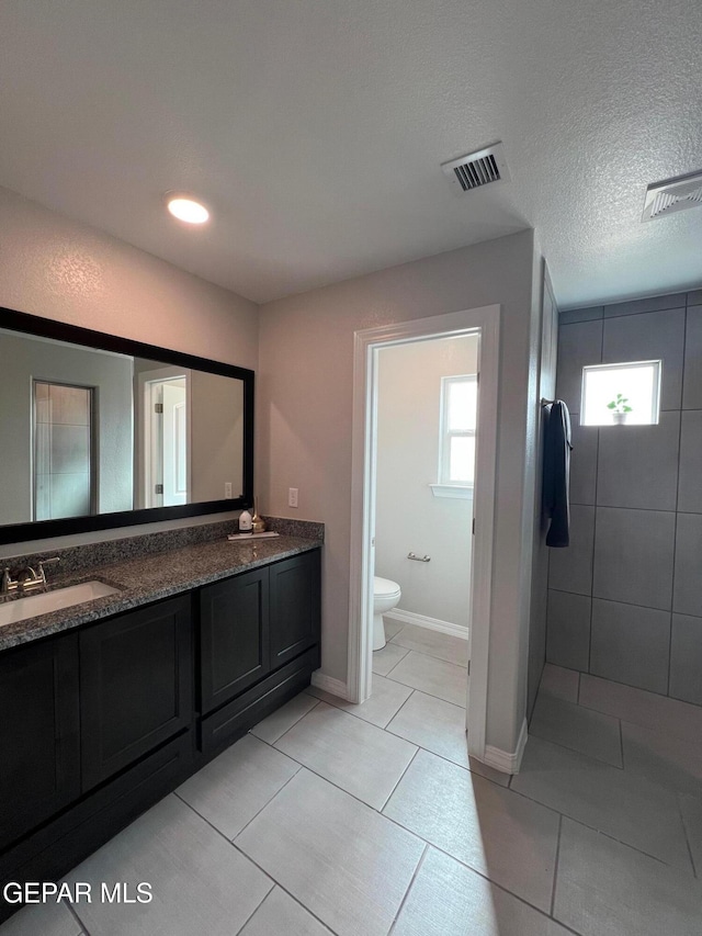 bathroom with double vanity, visible vents, toilet, tile patterned floors, and a sink