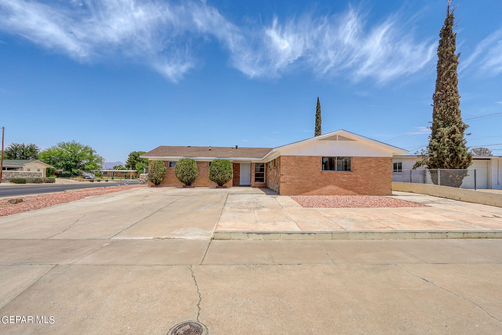 ranch-style home featuring fence and brick siding