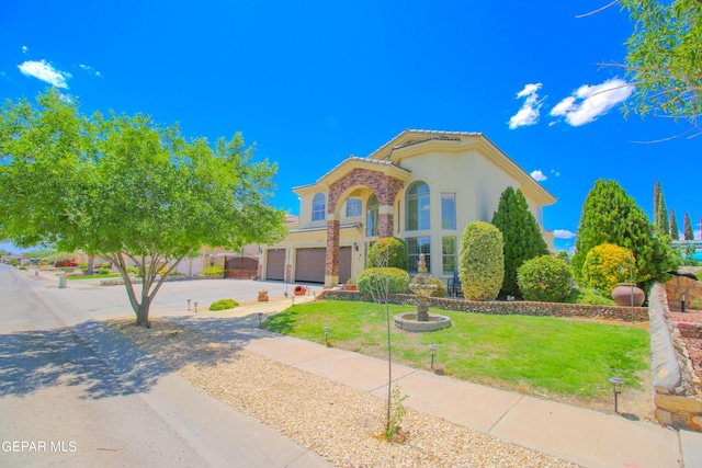 mediterranean / spanish home featuring a front lawn and a garage