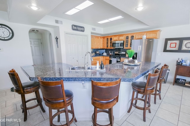 kitchen with sink, stainless steel appliances, a large island with sink, a kitchen bar, and light tile patterned floors