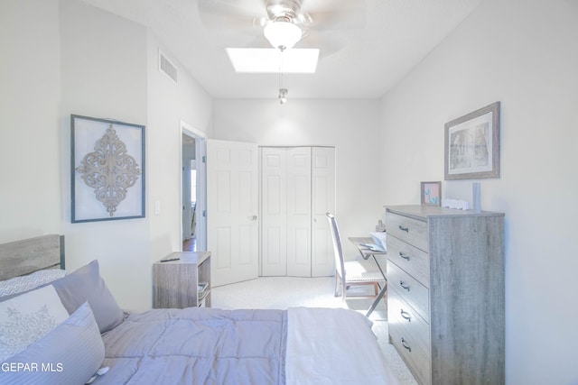 bedroom featuring ceiling fan, a skylight, light carpet, and a closet