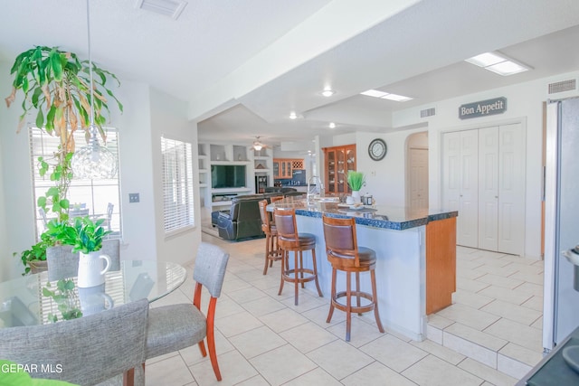 kitchen with a kitchen breakfast bar, kitchen peninsula, and light tile patterned floors