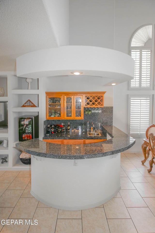 kitchen featuring kitchen peninsula, built in features, light tile patterned floors, and backsplash