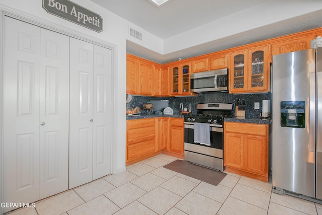 kitchen featuring decorative backsplash, appliances with stainless steel finishes, and light tile patterned floors