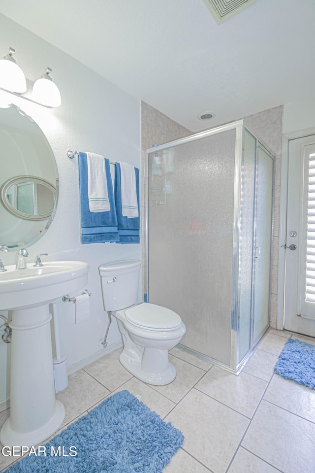 bathroom featuring tile patterned flooring, toilet, an enclosed shower, and sink