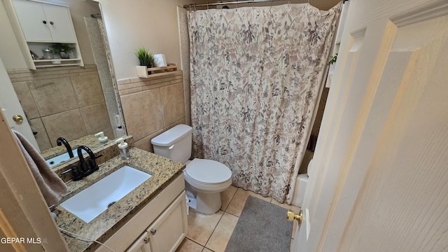 full bathroom with tile patterned floors, tile walls, toilet, vanity, and shower / tub combo