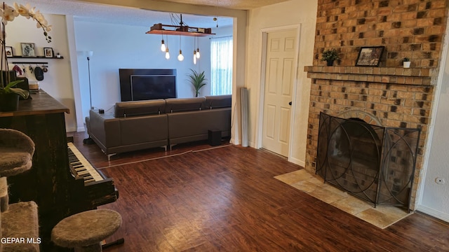 living room with hardwood / wood-style floors, a textured ceiling, and a brick fireplace