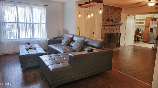 living room featuring ceiling fan, dark hardwood / wood-style flooring, and a fireplace