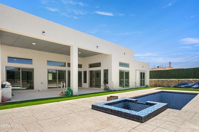 rear view of property featuring a swimming pool with hot tub and a patio