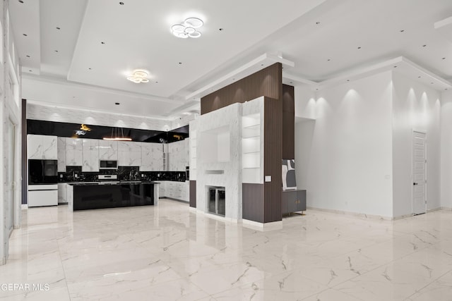 kitchen featuring a center island, refrigerator, a raised ceiling, a fireplace, and tasteful backsplash