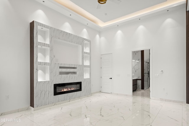 unfurnished living room with ceiling fan, a large fireplace, and a towering ceiling