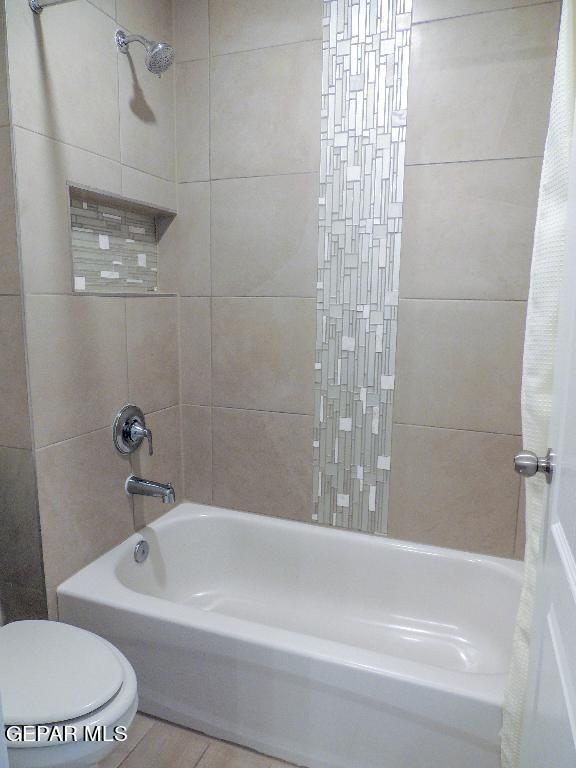 bathroom featuring toilet and shower / tub combo with curtain