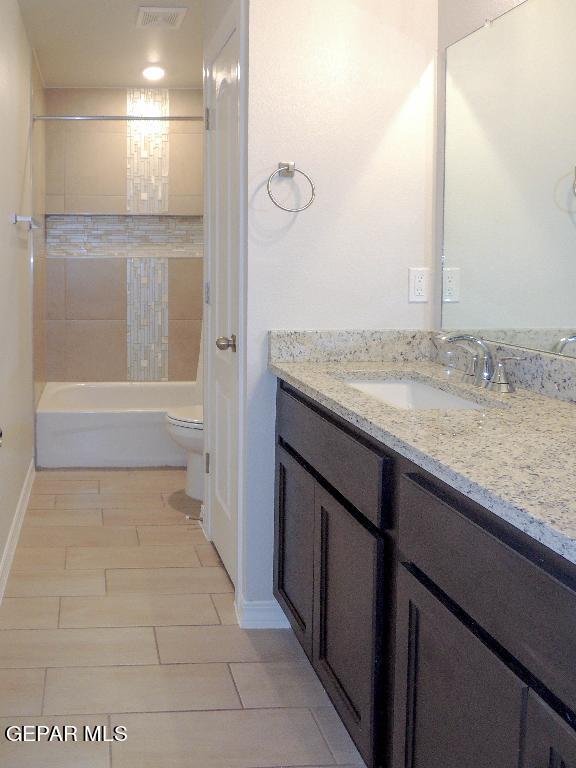 full bathroom featuring vanity, tiled shower / bath combo, and toilet