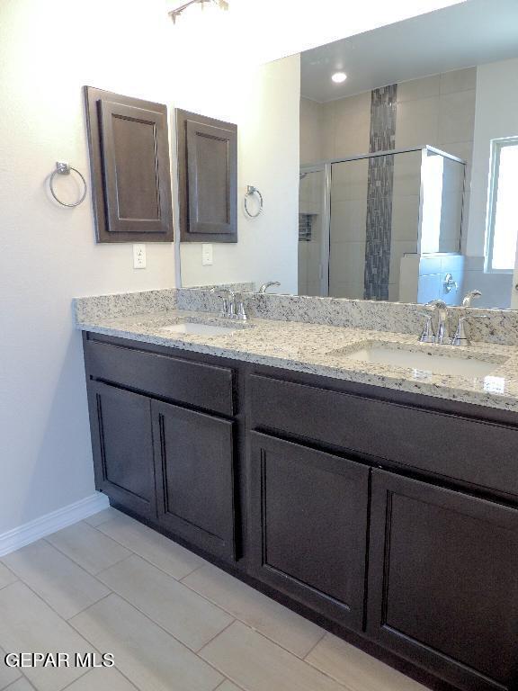 bathroom featuring a shower with door and vanity