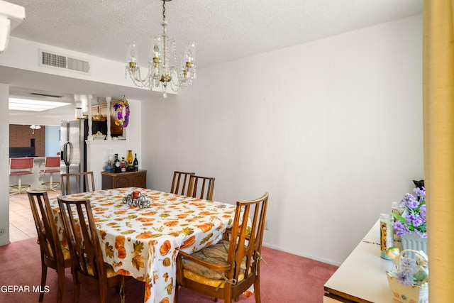 dining space with a textured ceiling, a chandelier, visible vents, and light colored carpet