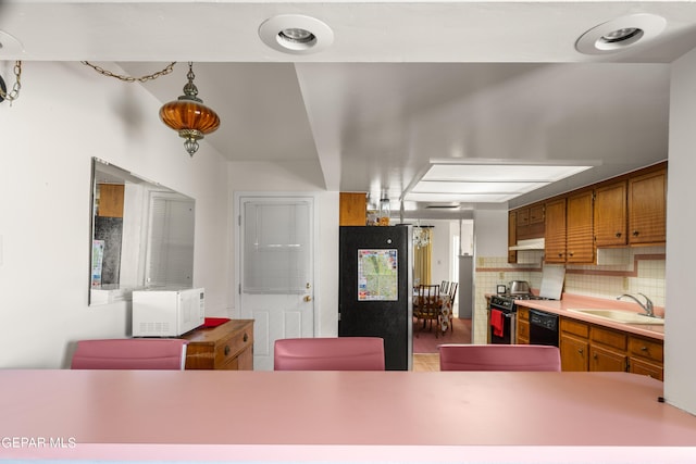 kitchen with a sink, light countertops, appliances with stainless steel finishes, decorative backsplash, and brown cabinetry