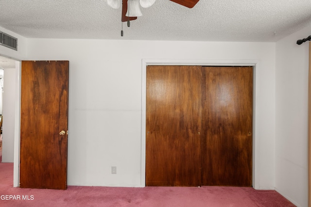 unfurnished bedroom featuring a textured ceiling, a closet, carpet, and visible vents