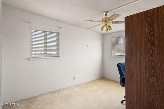 unfurnished office featuring carpet floors, a ceiling fan, and a textured ceiling