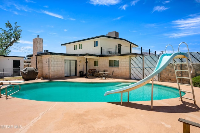 pool featuring fence, a diving board, a water slide, and a patio