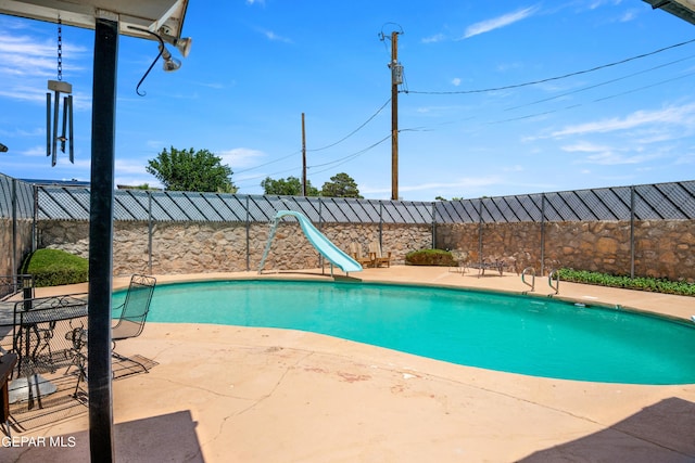 view of pool featuring a patio area, a water slide, and a fenced backyard