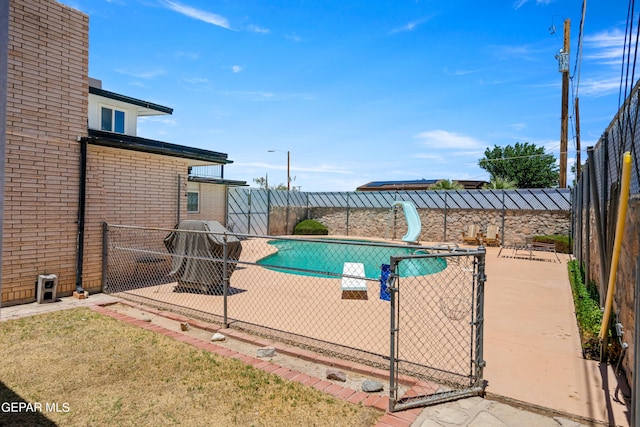 view of swimming pool featuring a patio area, a fenced backyard, a fenced in pool, and a water slide