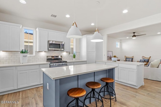 kitchen featuring white cabinetry, hanging light fixtures, ceiling fan, and stainless steel appliances