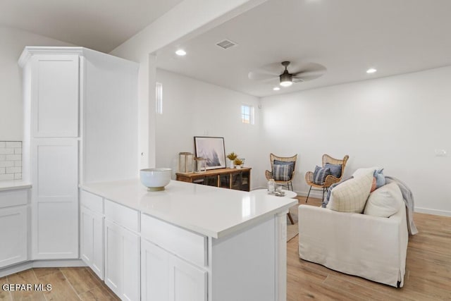 kitchen with kitchen peninsula, white cabinetry, ceiling fan, and light hardwood / wood-style floors