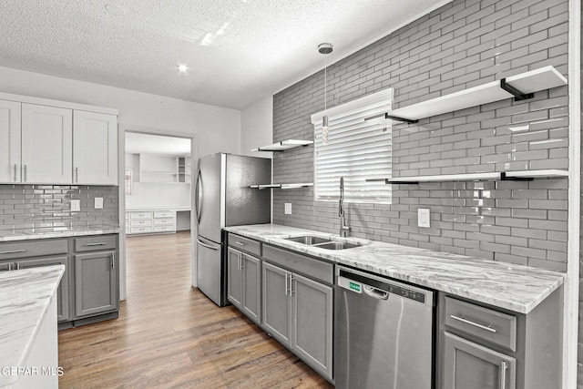 kitchen featuring pendant lighting, sink, hardwood / wood-style flooring, gray cabinets, and appliances with stainless steel finishes