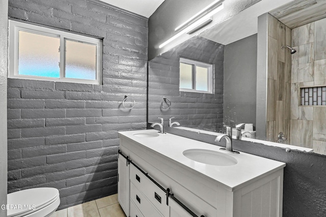 bathroom featuring tile patterned floors, vanity, toilet, and brick wall