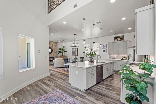 kitchen featuring a center island with sink, a stone fireplace, dark hardwood / wood-style floors, and sink