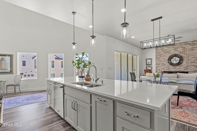 kitchen with dishwasher, a kitchen island with sink, dark wood-type flooring, sink, and decorative light fixtures