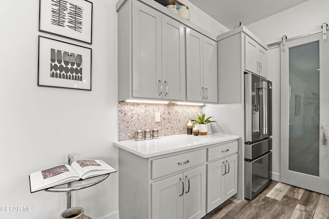 kitchen with backsplash, a barn door, high quality fridge, and dark hardwood / wood-style floors