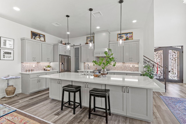 kitchen with premium range hood, french doors, light hardwood / wood-style flooring, a barn door, and high quality fridge