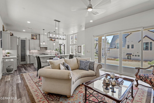 living room with sink, wood-type flooring, and ceiling fan with notable chandelier