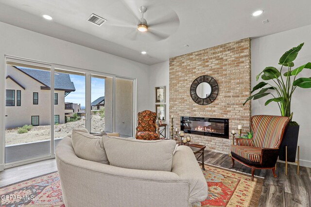 living room with a brick fireplace, ceiling fan, and hardwood / wood-style flooring