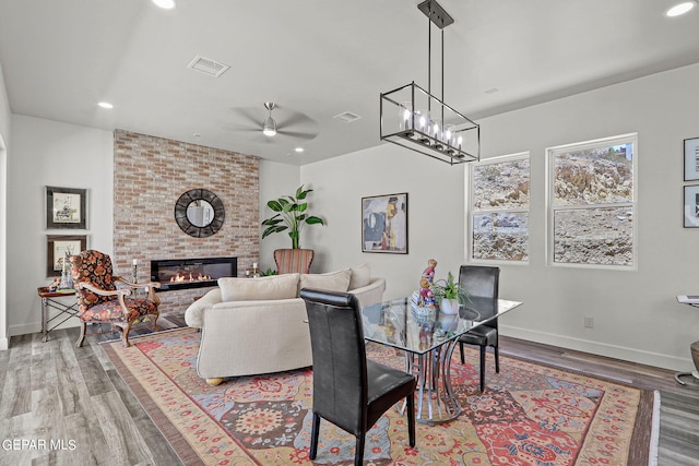 dining area featuring a fireplace, wood-type flooring, and ceiling fan