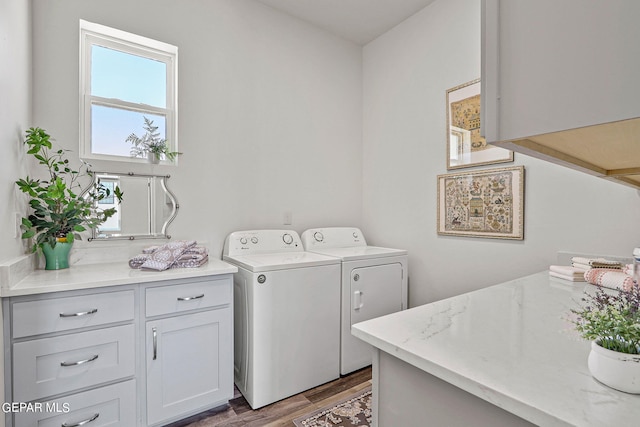 laundry room featuring washer and clothes dryer, cabinets, and wood-type flooring