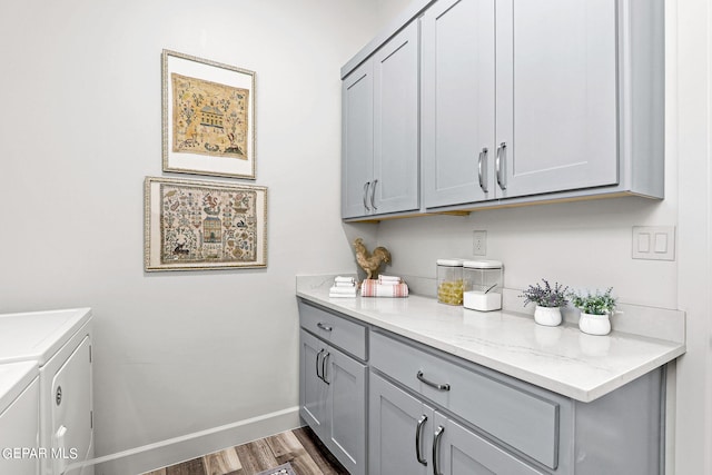 laundry room featuring washer and dryer, dark hardwood / wood-style flooring, and cabinets